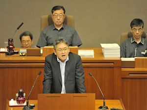 静岡県議会で「意見陳述」する請求代表者の1人、中村英一氏。うしろは小楠和男県議会議長
