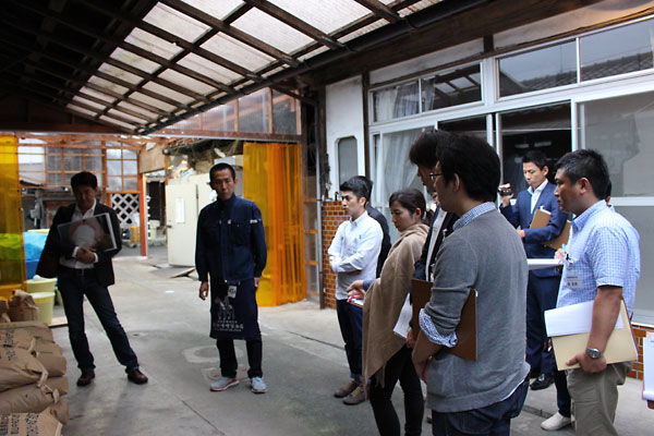 原発事故後の苦境を語る若松味噌醤油店の若松さん（左から2番目）の説明に、参加社員は熱心に耳を傾けていた。