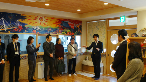 尾道拠点の施設内を案内する山田マネジャー（右から3人目）